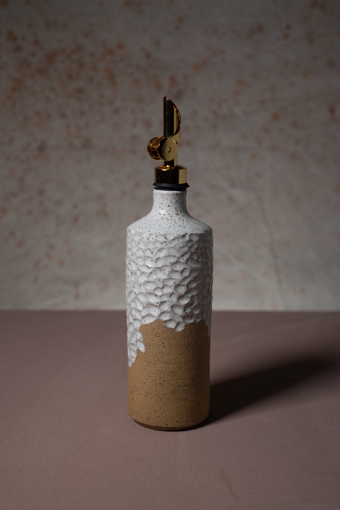 Hand made olive oil bottle featuring white glaze and a unique carving.
